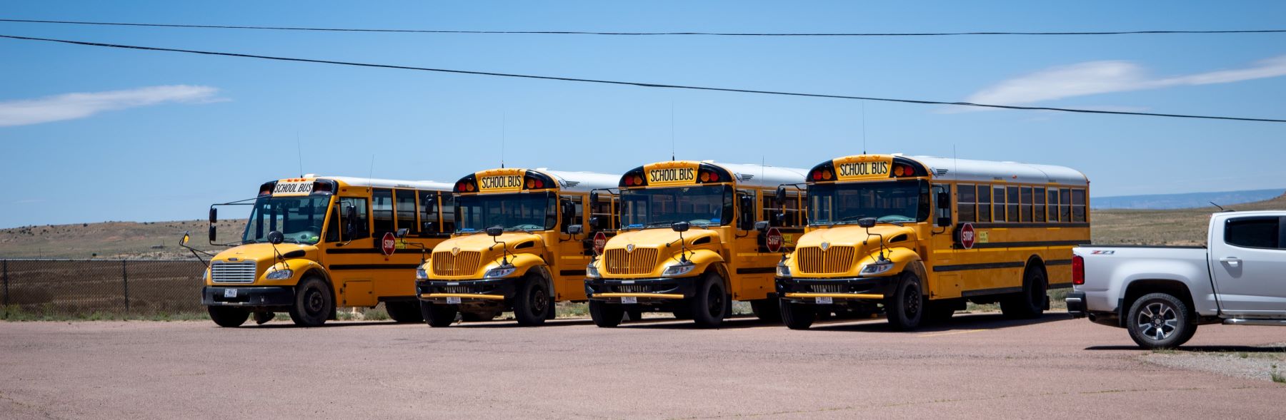 School buses parked in a line in parking lot.