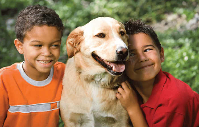 Two boys playing with their dog. 